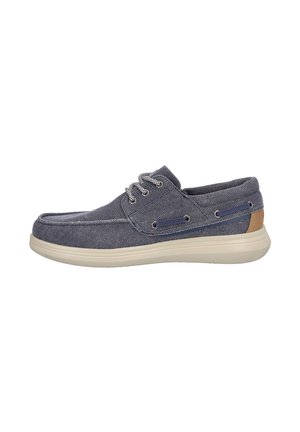 Zapato informal para hombre azul marino tipo slip-on con suela blanca, tela a rayas, punta redonda, cordones y detalle marrón en el talón.