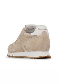 Baskets en daim beige avec un contrefort blanc, une tige texturée et une semelle en caoutchouc avec une semelle extérieure brun clair et un branding subtil.