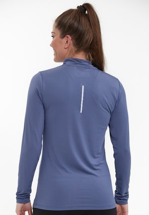 Haut de sport à manches longues en bleu profond, avec un col montant, une texture lisse et une bande réfléchissante verticale dans le dos.