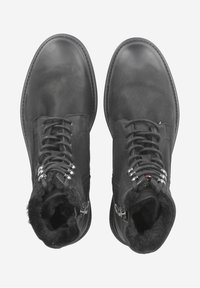 Bottes en cuir noir avec une texture lisse, dotées d'un haut tige, de lacets, de quincaillerie en métal argenté et d'un col doublé en fourrure pour la chaleur.