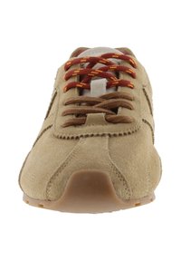 Zapatilla deportiva de gamuza beige con cordones de un patrón rojo y amarillo, diseñada con una punta redondeada y acentos marrones minimalistas en los lados.