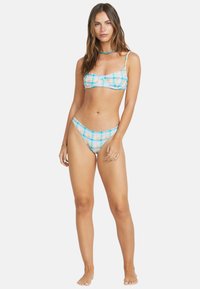 Bikini-Set mit einem pastellfarbenen Karomuster in Türkis, Pink und Gelb. Das Oberteil ist im Bralette-Stil mit verstellbaren Trägern; die Unterteile sind minimal.