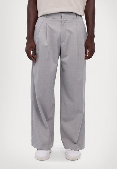 Gray tailored trousers with a wide-leg design, pleated front, and smooth texture, worn with white sneakers.