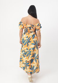 Maxikleid in Gelb mit blauen und weißen Blumenmustern. Geraffter Brustbereich mit schulterfreiem Ärmeldesign und fließendem Rock. Satinähnliche Textur.