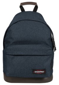 Mochila de tela azul oscuro con un compartimento principal con cremallera, bolsillo frontal, fondo de cuero marrón y una etiqueta con el logotipo negro de Eastpak.