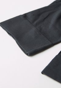 Tejido negro texturizado, mostrando una vista en primer plano del puño con un acabado suave. Un fondo gris claro mejora la visibilidad de los detalles.