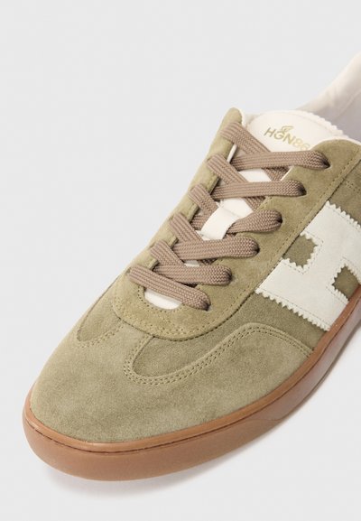 Olijfgroene suède sneaker met beige veters, off-white zijlogo en een bruine rubberen zool op een witte achtergrond.