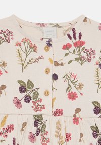 Kremfarget babykjole med rosa, lilla og grønne blomster- og bærtrykk, med tre brune knapper og rund halslinning.