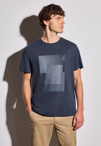 T-shirt en coton bleu marine avec un imprimé graphique géométrique dans des teintes plus claires, à manches courtes et à encolure ronde.