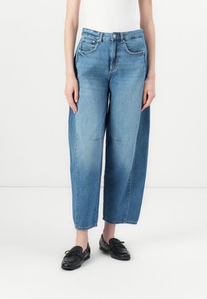 Lichtblauwe denim wijde pijpen jeans met een hoge taille, voorzien van zijzakken en stikdetails. Gecombineerd met zwarte schoenen.