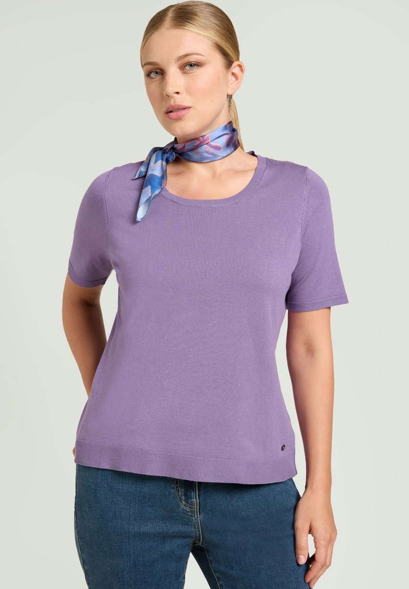 Suéter lila de manga corta con escote redondo, bordes acanalados, textura suave, combinado con una bufanda azul con estampado atada alrededor del cuello.