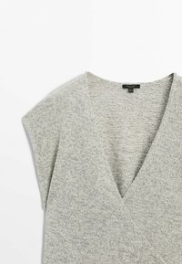 Haut tricoté gris clair à manches courtes avec un profond décolleté en V et un devant style cache-cœur, présenté à plat sur fond blanc.