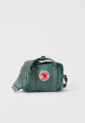 Petit sac Fjällräven Kånken vert avec bandoulière réglable et patch logo sur le devant, sur fond uni.