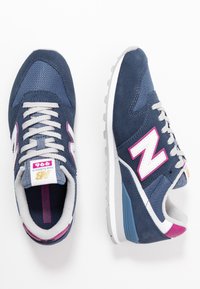 Mörkblå sneakers i en kombination av mocka och nätmaterial. Har en rosa detalj, vit "N"-logotyp, grå snören och en vit mellansula.