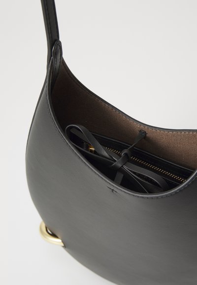 Black leather shoulder bag with a curved shape, featuring a brown fabric interior, a gold zipper pocket, and black ribbon accents.