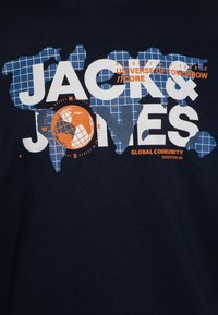 Camiseta azul marino con un diseño gráfico texturizado en blanco y naranja, que muestra "JACK & JONES" y una ilustración de un globo.