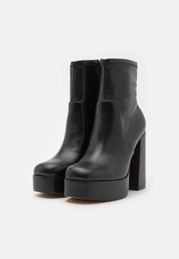 Black leather ankle boots with a sleek design, featuring a round toe, platform sole, and block heel. Smooth texture and zipper closure.