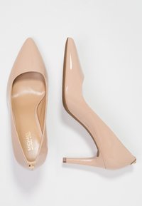 Escarpins en cuir verni couleur nude, à bouts pointus et talons aiguilles de 10 cm. Dotés d'une doublure intérieure et d'un discret accent métallique à l'arrière.