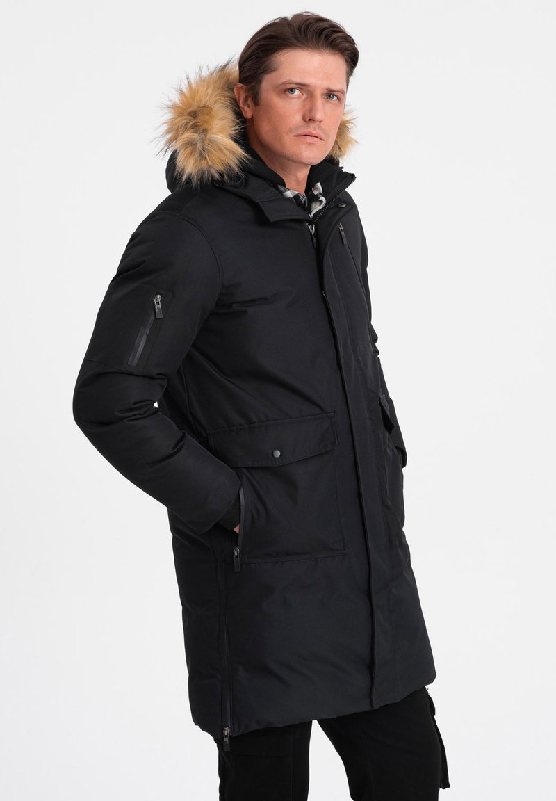 Giacca parka nera con cappuccio foderato in pelliccia, dotata di tasche con zip e a soffietto, maniche lunghe e vestibilità morbida. Tessuto liscio, materiale resistente all'acqua.
