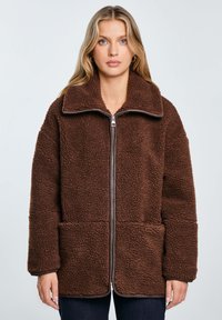 Braune Fleecejacke mit hohem Kragen, Frontreißverschluss und zwei Seitentaschen, mit einer strukturierten, weichen Oberfläche und einem lässigen Schnitt.