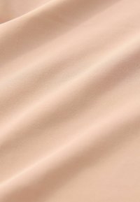 Glatter, hellbeiger Stoff mit subtilen diagonalen Falten und feiner Strickstruktur, Nahaufnahme.