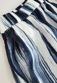 Navy and white patterned fabric shorts with a crinkled texture and elastic waistband, featuring wavy stripes for visual interest.