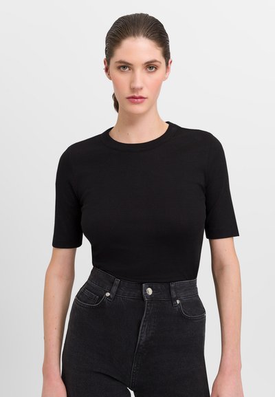 Zwart geribbeld t-shirt met korte mouwen en een ronde halslijn, gecombineerd met hoge zwarte jeans met knoopsluiting en steekzakken aan de voorkant.