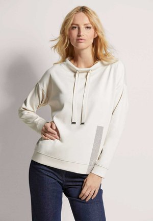 Helle Creme Kapuzenpullover mit lockerer Passform, verstellbaren Kordeln und einem strukturierten Mesh-Akzent an der unteren Seite. Weicher Stoff mit gerippten Bündchen.