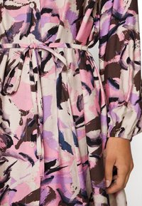Langärmliges Kleid aus leichtem Material mit einem abstrakten Muster in Rosa, Lila und Braun, ausgestattet mit einem passenden Gürtel und einer Knopfleiste.