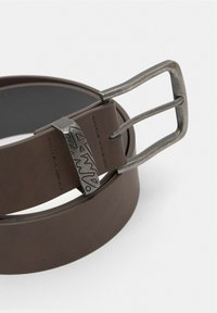 Brown leather belt with a textured surface and a metal buckle featuring an engraved design. The belt is close to a white background.