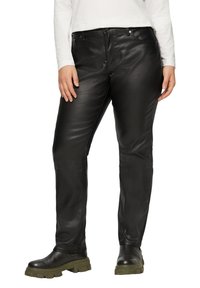 Schwarze Lederhosen mit schmalem Schnitt, ausgestattet mit Fronttaschen, einer glatten Textur und kombiniert mit klobigen schwarzen Stiefeln.