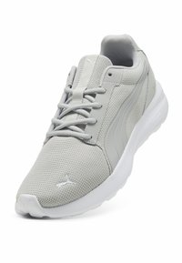 Zapato deportivo gris con parte superior de malla, cuello acolchado y suela de goma blanca. Presenta una superficie texturada y un detalle de logo prominente.