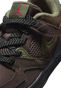 Brązowy but sportowy z siateczkowym i zamszowym materiałem, czarno-zielone akcenty, teksturowane sznurowadła oraz czerwone logo na języku.