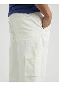 Shorts cargo couleur crème avec de multiples poches, une coupe droite et une texture lisse avec des détails de couture renforcée.