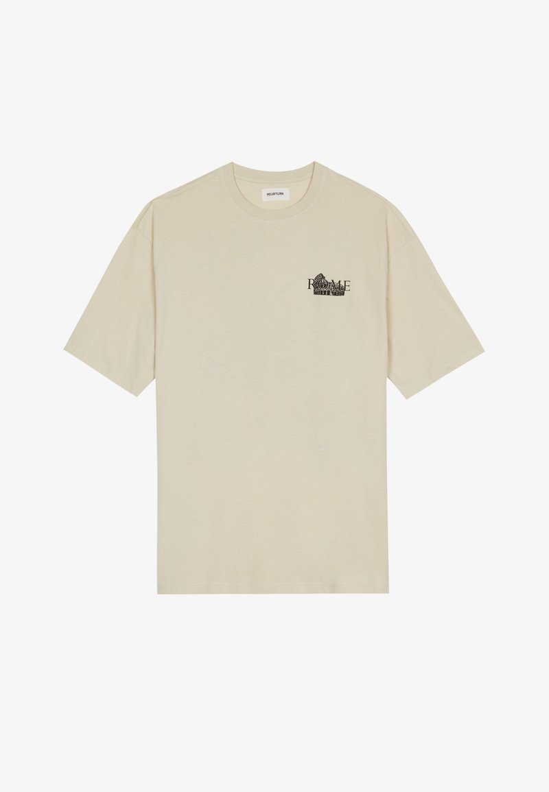 Beige pamut póló rövid ujjakkal, kerek nyakkal, elöl fekete grafikával, amelyen "ROME" felirat szerepel.