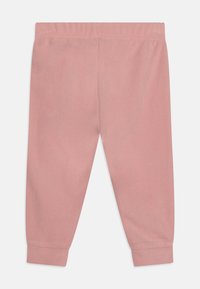 Sanfte pinke Sweatpants aus Fleece-Material, ausgestattet mit einem elastischen Bund, schmal zulaufenden Bündchen und einer glatten Textur. Einfaches, einfarbiges Design.