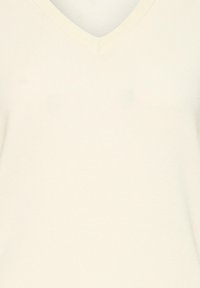 Top s výstrihom do V a krátkymi rukávmi v krémovej farbe, vyrobený z rebrovanej tkaniny s hladkou textúrou. Jednoduchý dizajn bez vzorov alebo ozdôb.