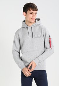 Felpa grigia in cotone con tasca frontale, cappuccio con lacci regolabili e una cerniera rossa di accento sulla manica sinistra. Design semplice.