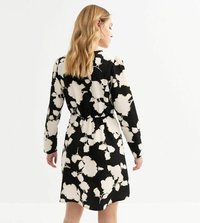 Robe noire avec un motif floral blanc, manches longues et taille élastique. Tissu fluide avec une coupe mi-long et un col rond.