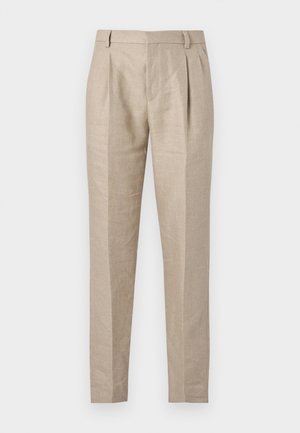 Pantalones beige a medida con pliegues delanteros, presillas para cinturón y piernas estrechas y cónicas sobre un fondo blanco.