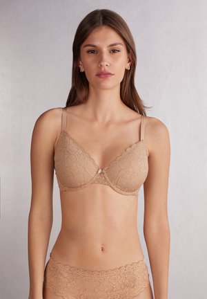Kanten bralette in een huidskleur, met een driehoekige vorm, verstelbare bandjes en een delicate strikaccent in het midden.