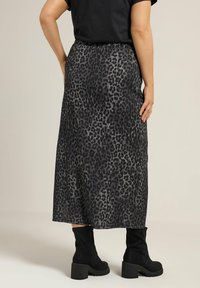 Maxi rok met luipaardprint in grijs en zwart, met een elastische tailleband en een vloeiende stijl. Draag het met zwarte kniehoge laarzen.