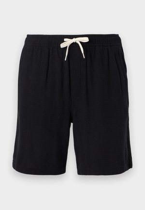 Mustat rennot shortsit, joissa joustava vyötärönauha ja valkoinen kiristysnauha, sivutaskuilla, esillä vaaleaa taustaa vasten.