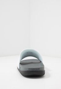 Šviesiai mėlynos šlepetės su juodu putų padu. Pado vidus turi tekstą "revive foam", o dizainas pasižymi lygiu, minimalistiniu pavidalu.
