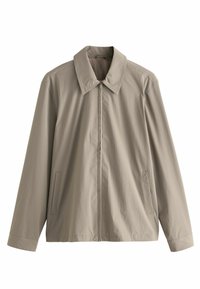 Chaqueta beige clara con un collar estructurado, cremallera frontal y bolsillos laterales. Hecha de una tela suave y ligera con costuras mínimas.