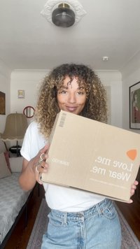 Καφέ χαρτονένιο κουτί με το κείμενο "Αγάπα με. Φόρεσέ με." και το όνομα της μάρκας "zalando." Κρατείται σε χέρια με ασημένια δαχτυλίδια.