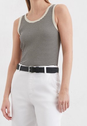 Débardeur rayé noir et crème avec une texture côtelée, doté d'un col crème contrastant. Assorti à un pantalon blanc taille haute et une ceinture noire.