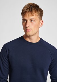 Middengrijze sweatshirt met een ronde halslijn, raglanmouwen en een zachte textuur. Eenvoudig ontwerp zonder patronen of zichtbare hardware.