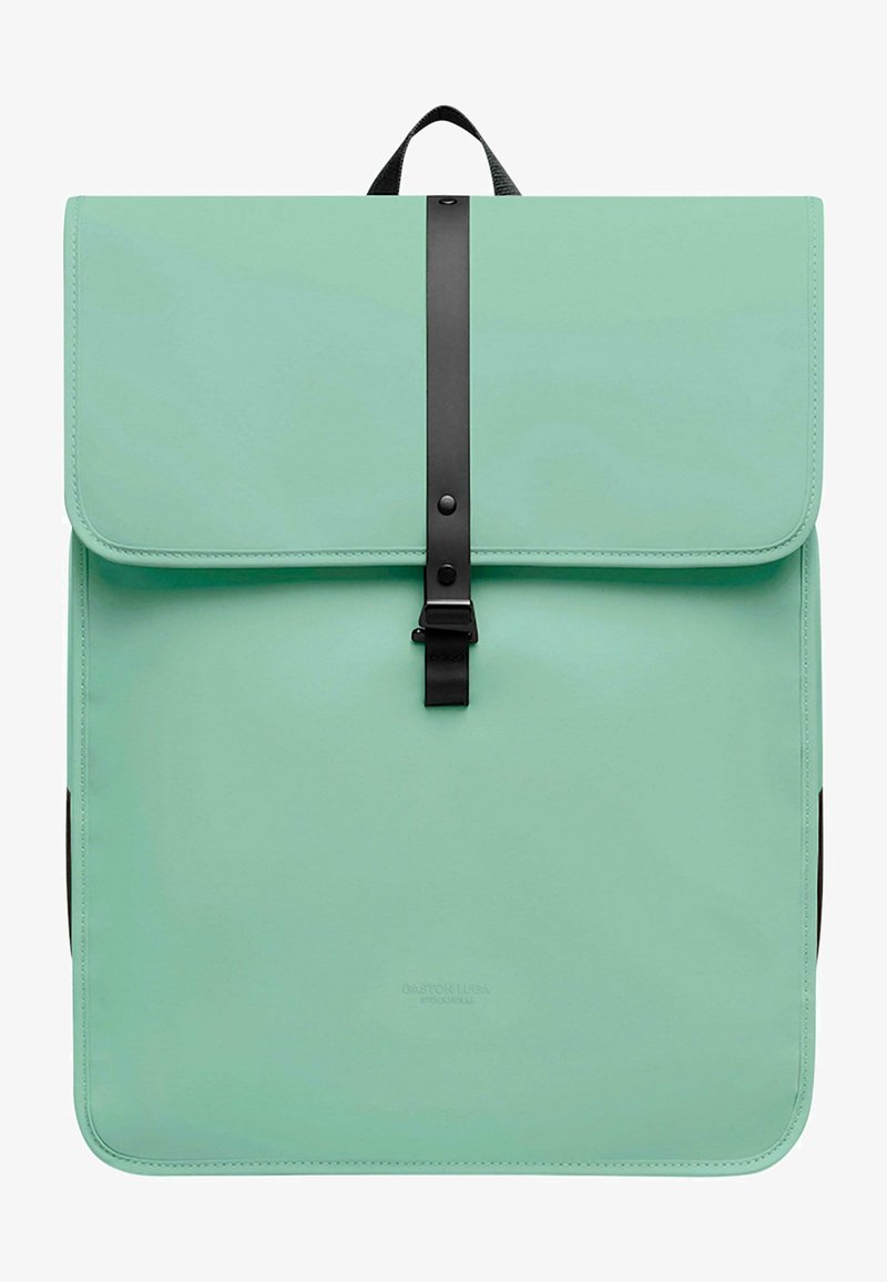Mintgrønn ryggsekk laget av syntetisk materiale, med klaffelukking som har en svart stropp og spenne, teksturert overflate og avrundede kanter.