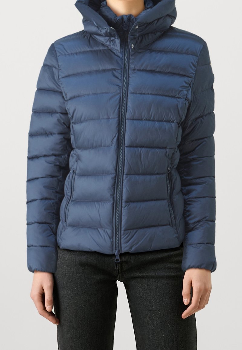 Giacca trapuntata blu navy con zip frontale, design trapuntato orizzontale e cappuccio. Dotata di tasche laterali e polsini elasticizzati per garantire comfort.